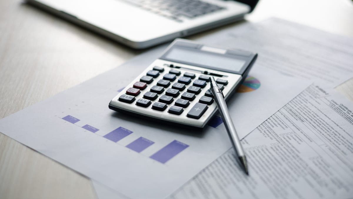 Taschenrechner, Kugelschreiber und Finanzunterlagen auf dem Schreibtisch als Sinnbild der Kalkulation für einen professionell erstellten Businessplan